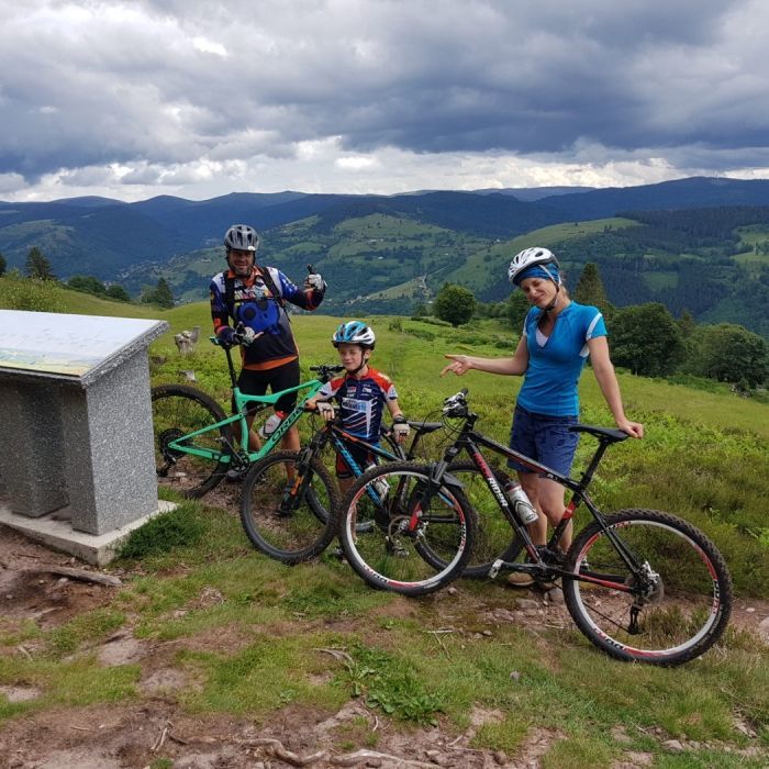 Family mountain biking at the top of a Vosges pass with panoramic view