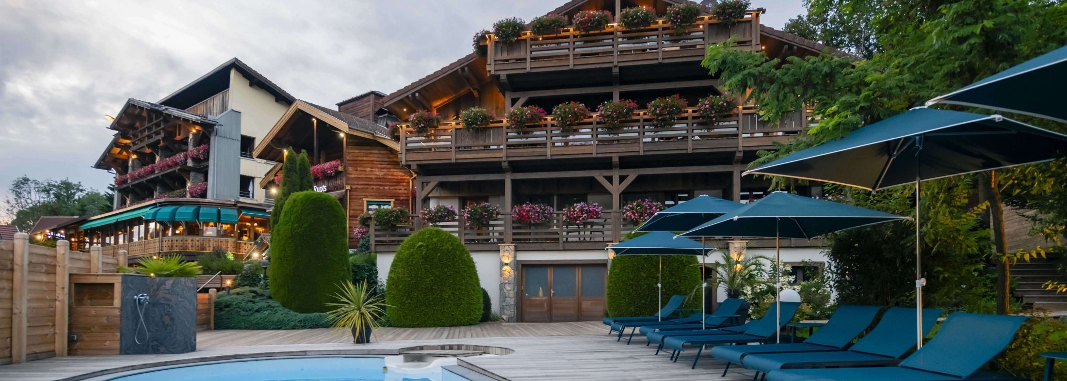 Façade de l’hôtel Les Bas Rupts dans la forêt vosgienne, avec piscine extérieure et transats, à 800 mètres d’altitude