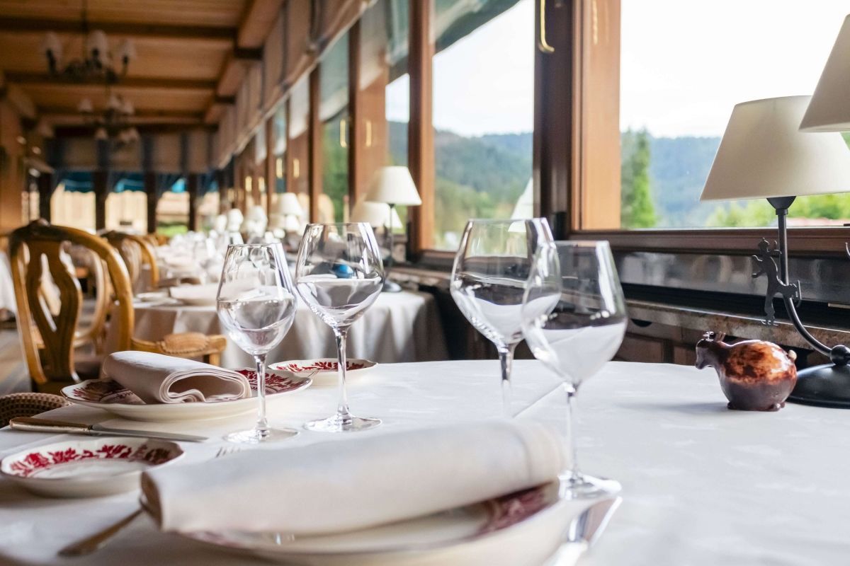 Table dressée dans la salle panoramique du restaurant Les Bas Rupts avec vue sur la montagne et accès à une cave à vins d’exception