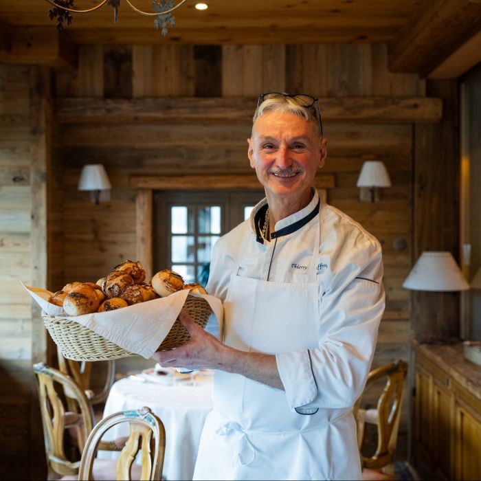 Le chef pâtissier Thierry Mauffrey tenant un panier de pains frais au restaurant Les Bas Rupts, passionné par les desserts classiques depuis 1987