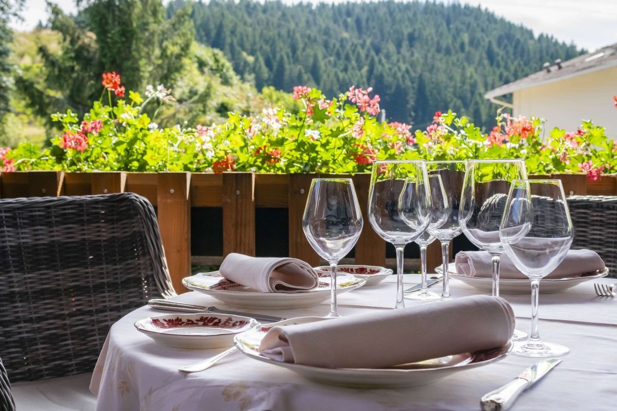 Set table on the flowered terrace of Les Bas Rupts restaurant with forest view