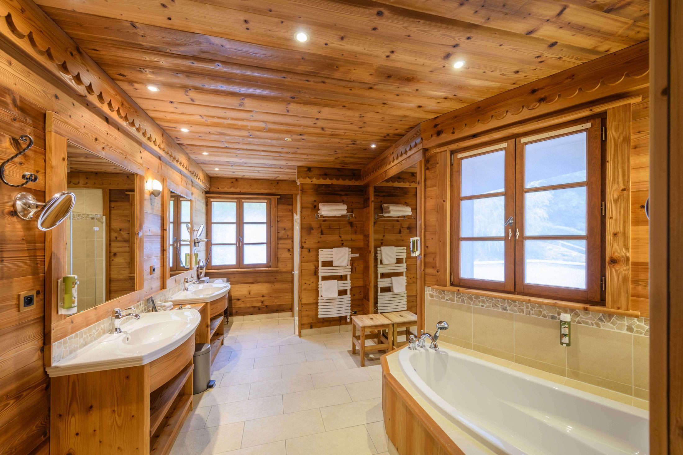 Suite de 110m² à l’esprit chalet avec poutres apparentes, salon, dressing, grande terrasse et salle de bains avec baignoire et douche.