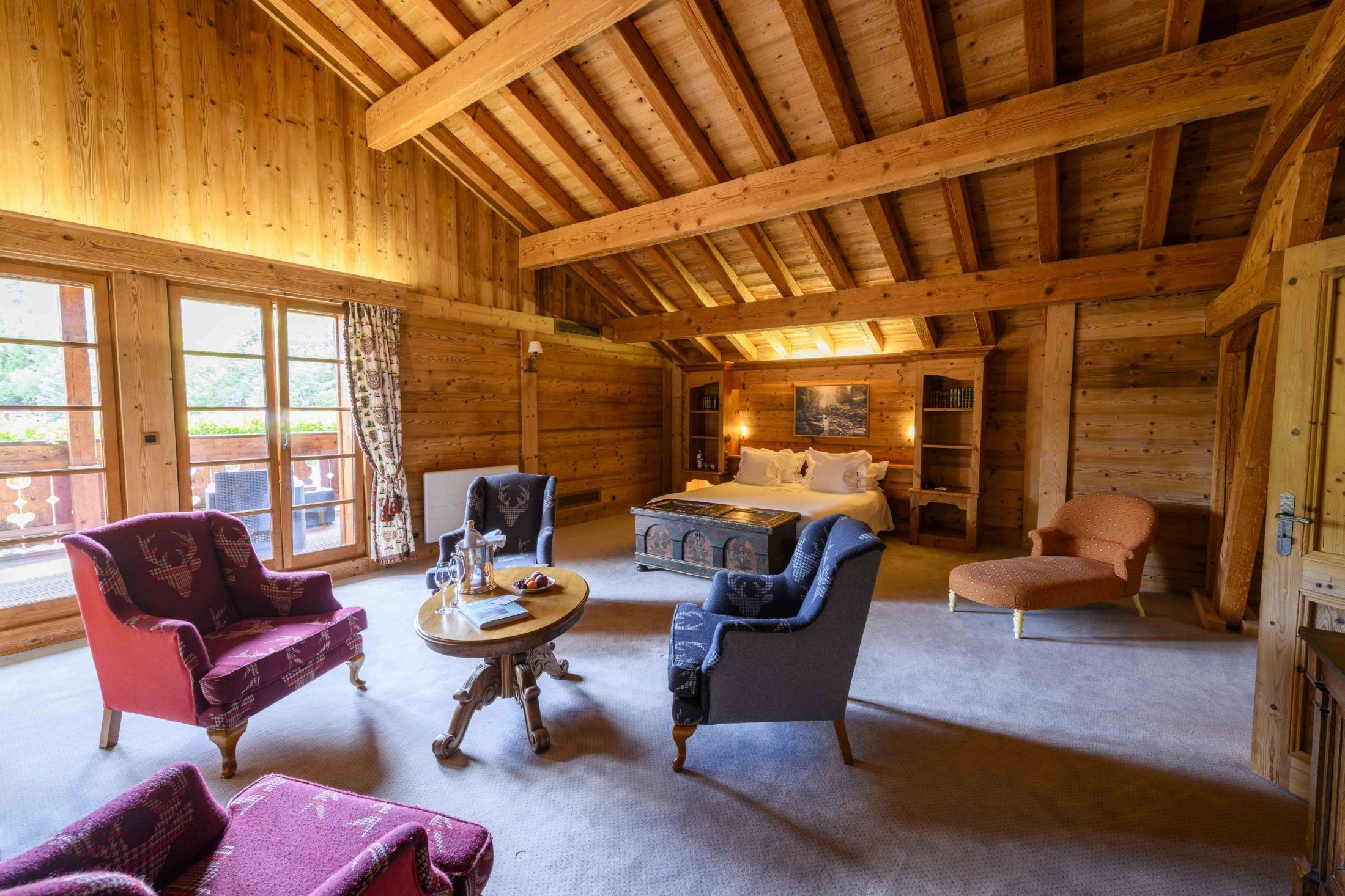 Suite de 110m² à l’esprit chalet avec poutres apparentes, salon, dressing, grande terrasse et salle de bains avec baignoire et douche.