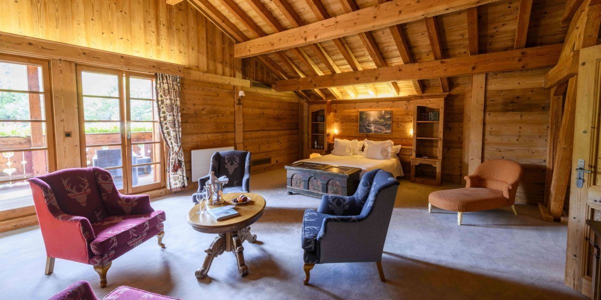 110m² chalet-style suite with exposed beams, living room, walk-in closet, large terrace, and bathroom with bathtub and shower.