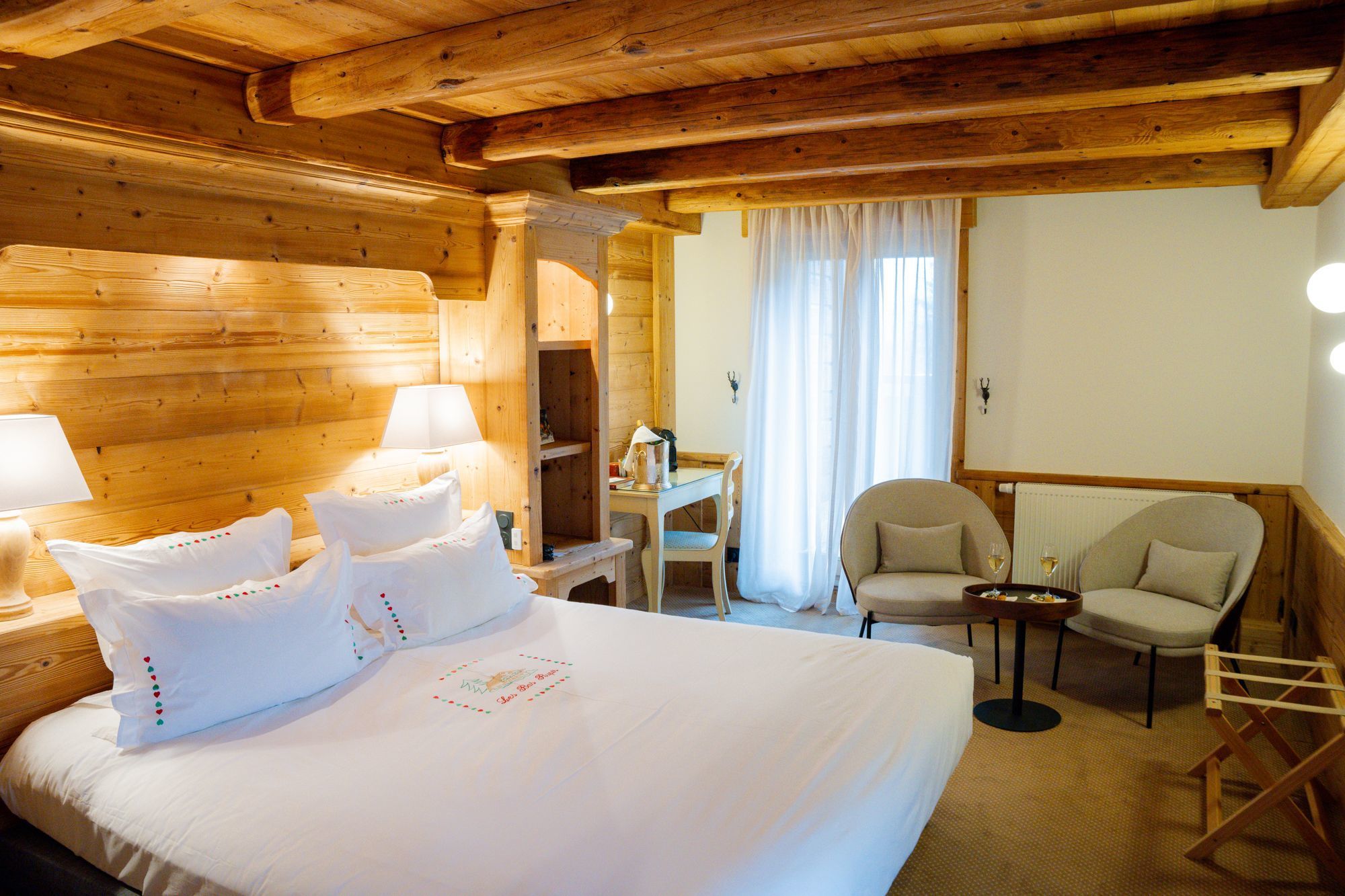 Chambre Charme de l’hôtel Les Bas Rupts, style chalet chaleureux avec terrasse privative, vue montagne et piscine extérieure