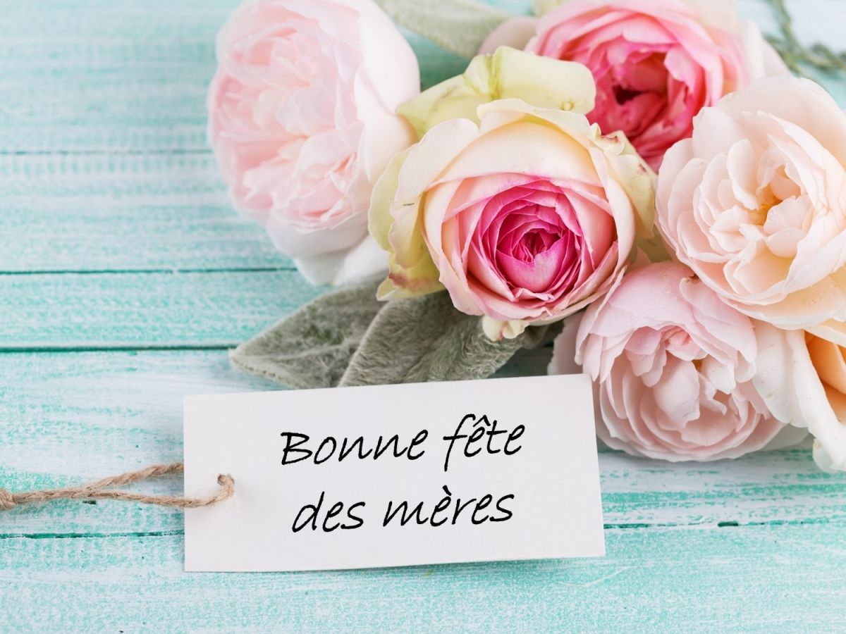 Pastel rose bouquet with a tag reading "Happy Mother's Day" on a turquoise wooden background.