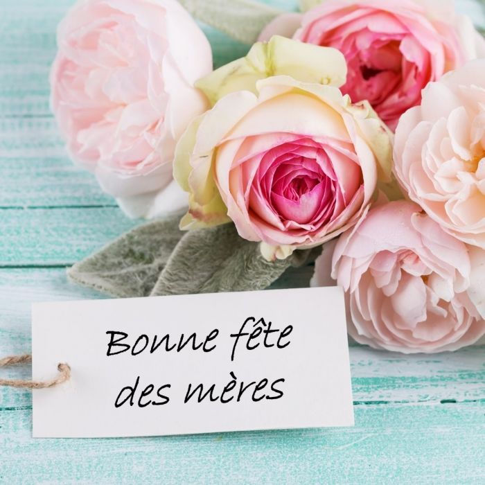 Pastel rose bouquet with a tag reading "Happy Mother's Day" on a turquoise wooden background.