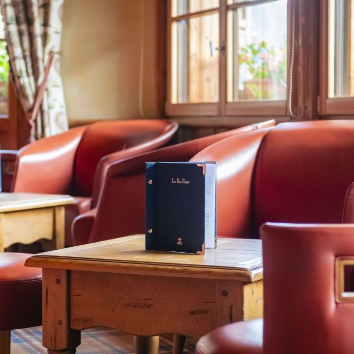 Cosy lounge armchairs and Les Bas Rupts bar menu in a bright setting in Gérardmer.